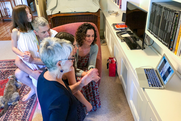 Summer Christmas morning: Three generations of family chat with overseas members via laptop Multi-generational family chatting with overseas members via internet and laptop computer